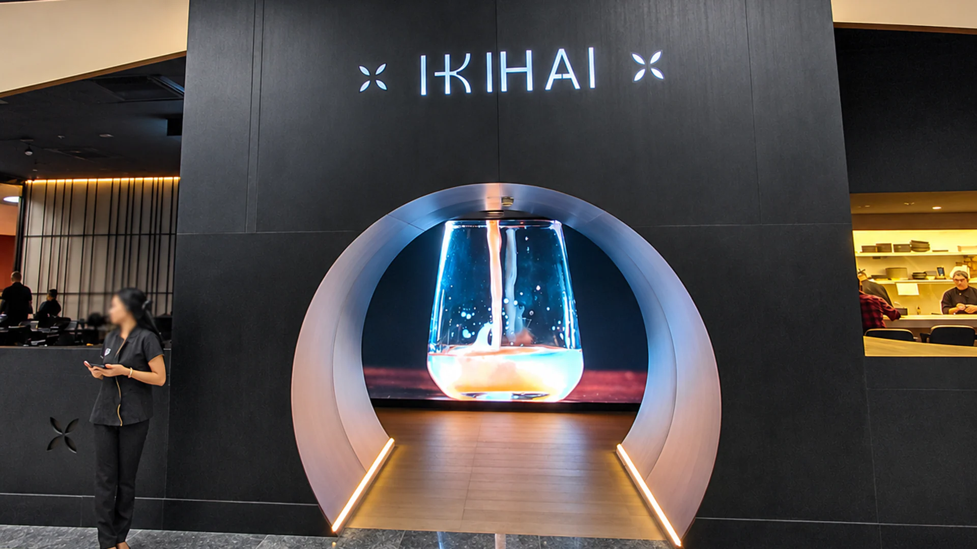 Fotografia real da entrada do Ikihai no Shopping Metrô Tatuapé, com portal circular iluminado, revestimento escuro e áreas de atendimento