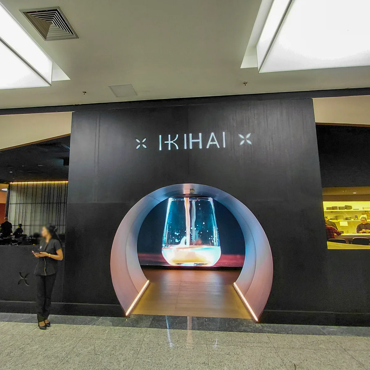 Fotografia real da entrada do Ikihai no Shopping Metrô Tatuapé, com portal circular iluminado, revestimento escuro e áreas de atendimento